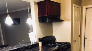 A kitchen with dark wooden cabinets, a black stove, and a granite countertop.