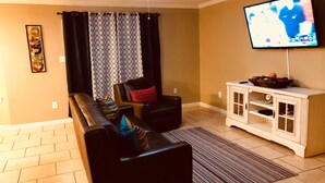 A living room with a sofa, a chair, a television, and a cabinet.