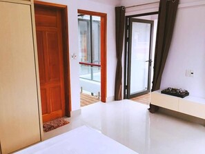Una habitación con puerta de madera, puerta corredera de vidrio y un banco blanco.