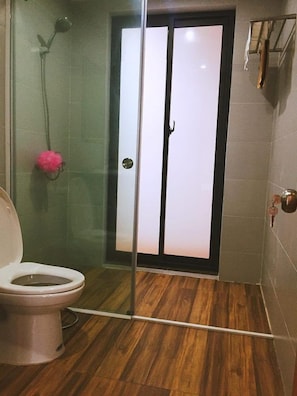 A bathroom with a glass shower enclosure, a toilet, and a wooden floor. - D'Home Homestay Cat Ba (Hai Phong)