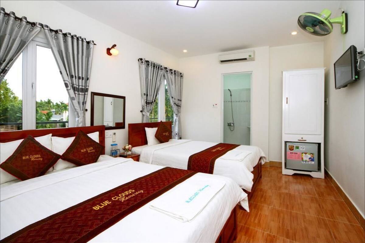 A hotel room with two beds, a TV, a minibar, and a shower area.