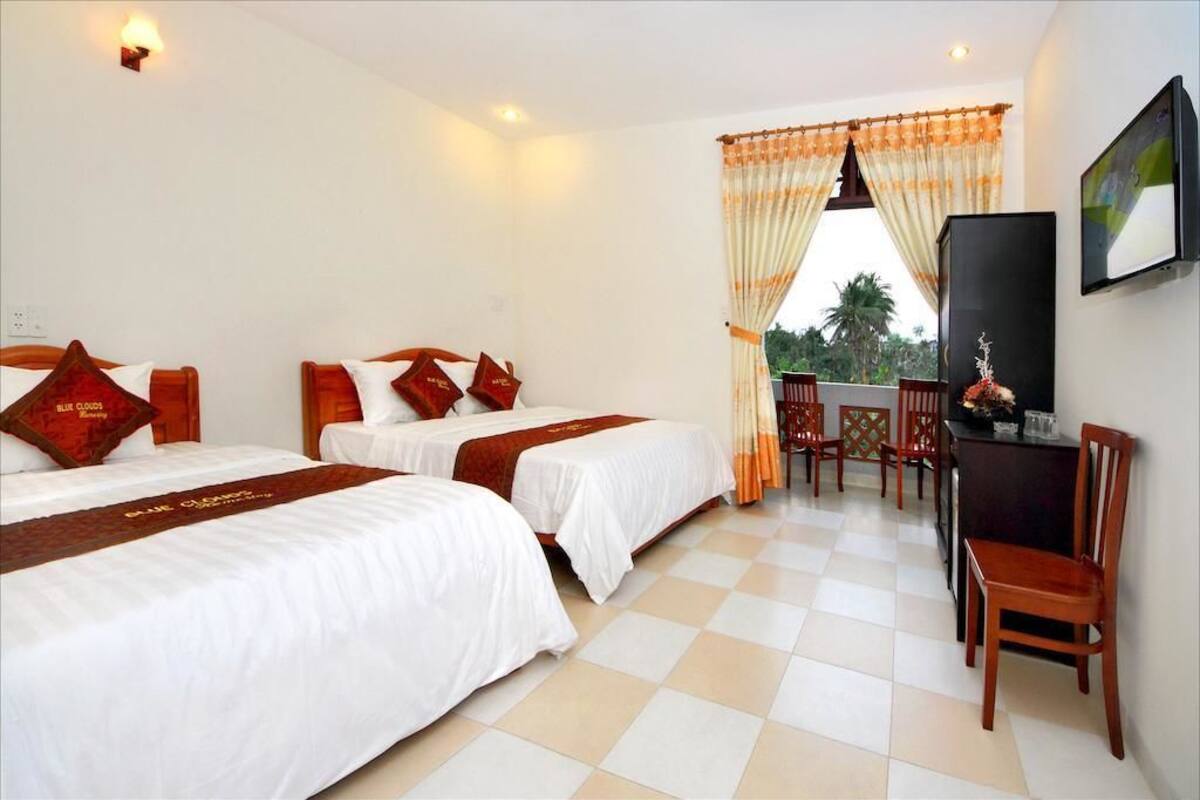 A hotel room with two beds, a desk, and a chair.
