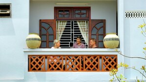 A balcony with a lattice railing, a window with decorative wooden frames, and two large vases on either side. - Blue Clouds Homestay (Da Nang)