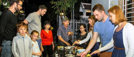 A group of people gathered around a table with food and drinks, possibly at an outdoor event or gathering.