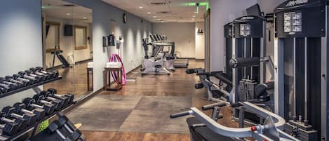 Un gimnasio con equipo de ejercicio, un espejo y suelo de madera.