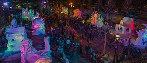 Una multitud se reunió alrededor de esculturas de hielo iluminadas en un espacio al aire libre.