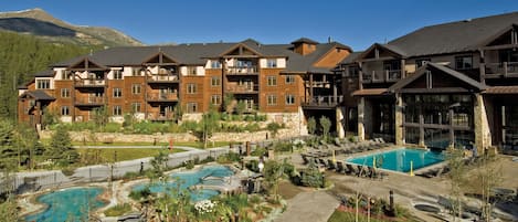 A resort with multiple buildings, a central pool area, and a mountain backdrop.