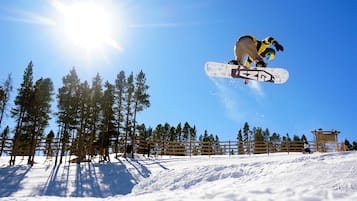 A snowboarder performing a jump with a clear sky and trees in the background.
