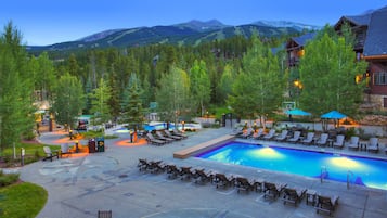 Ein Poolbereich eines Resorts mit Liegestühlen, einem Schwimmbecken und einer Bergkulisse.