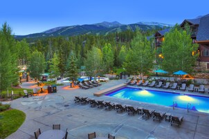 A resort pool area with lounge chairs, a swimming pool, and a mountainous backdrop.