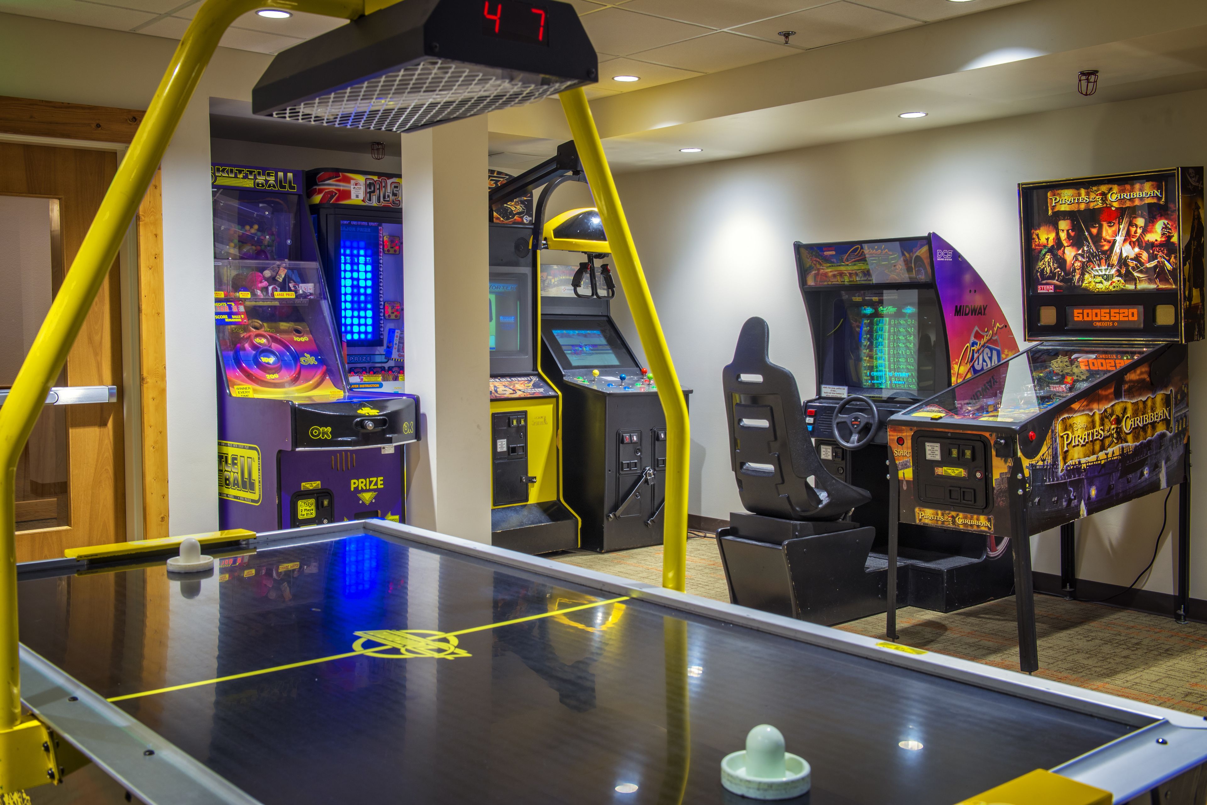 A pool table with a digital scoreboard, arcade games, and a seating area.