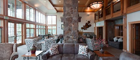 A spacious lobby with a large stone pillar, leather sofas, and a wooden coffee table.