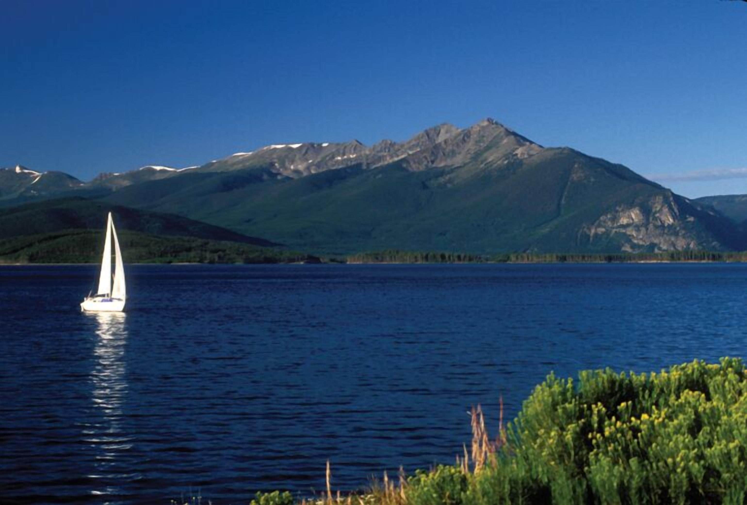 A sailboat on a calm lake with mountains in the background.