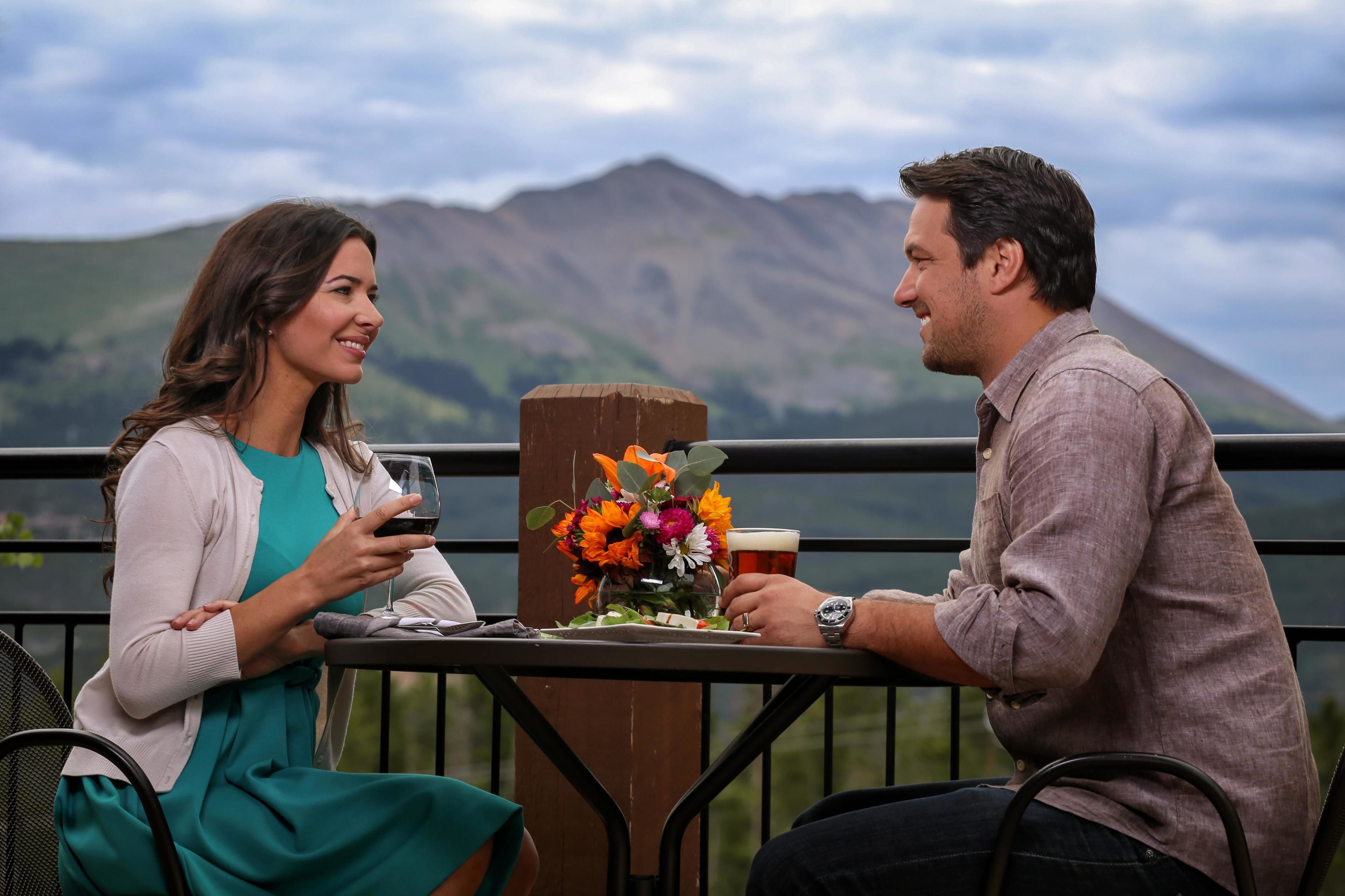 Two people seated at a table with a view of mountains in the background.