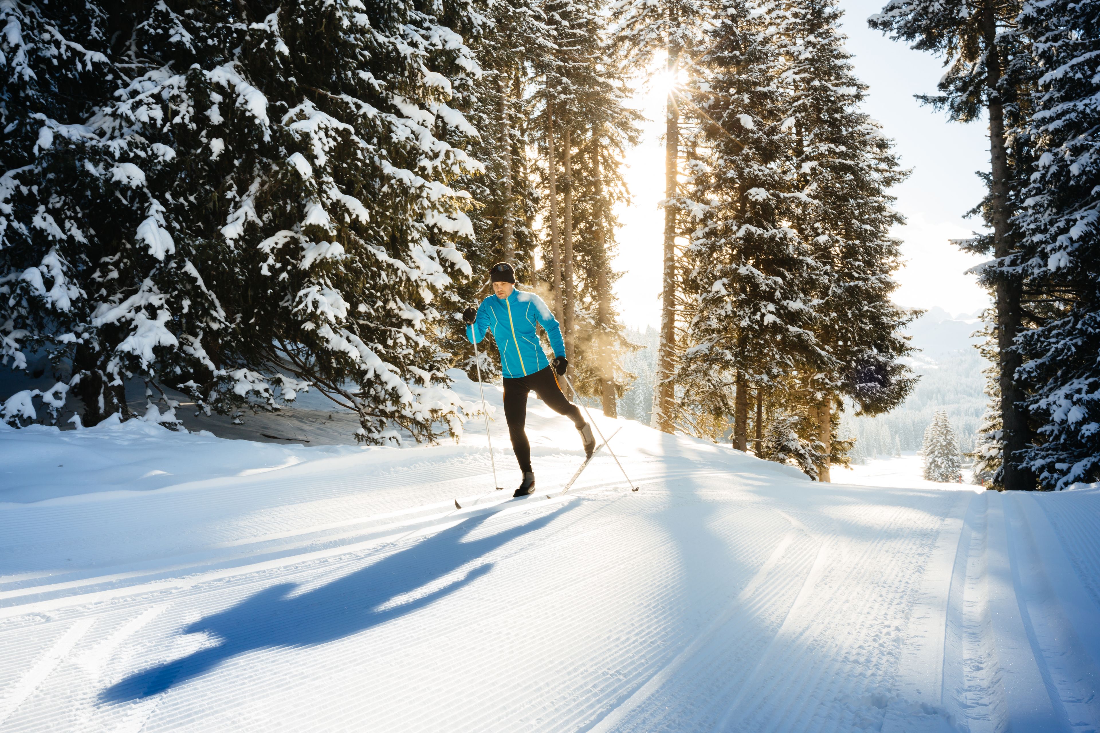 A person skiing on a snow-covered path surrounded by trees.
