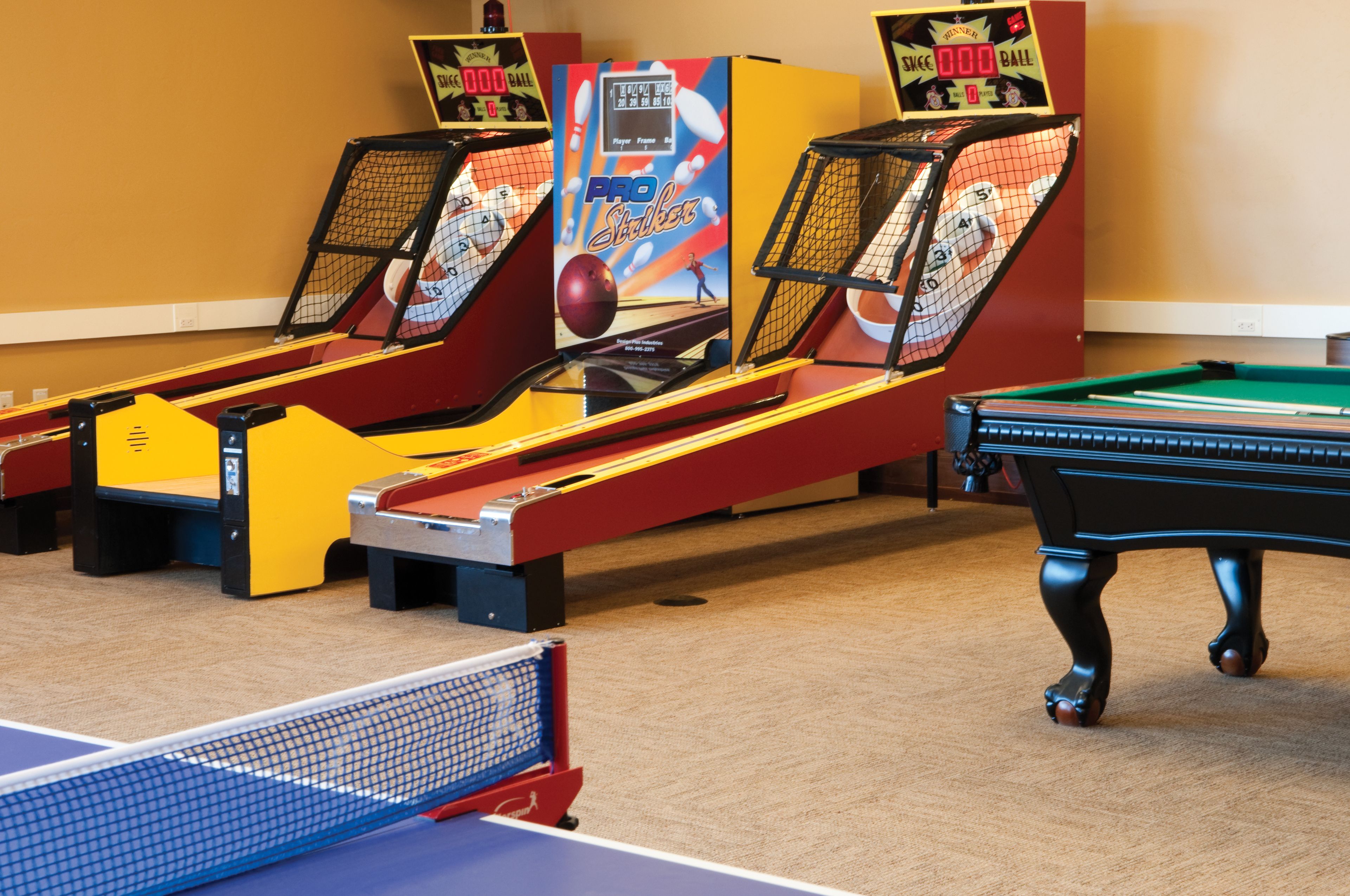 Ein Billardtisch, ein Pooltisch und zwei Bowling-Automaten in einem Raum.