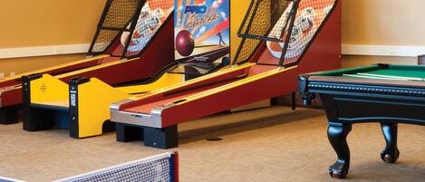 Ein Billardtisch, ein Pooltisch und zwei Bowling-Automaten in einem Raum.