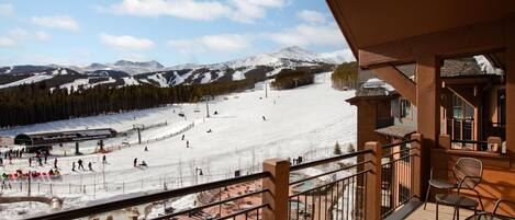 A balcony with a view of a ski resort, including a ski lift and a snow-covered mountain.