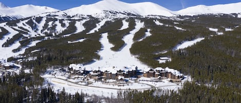 A snow-covered mountain with a ski resort and lodge in the valley.