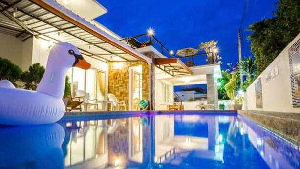 A swimming pool with a swan float, indoor seating, and a view of the outdoors. - Timeless Pool Villa Huahin (Hua Hin)
