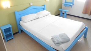 A single-bed room with a blue headboard, white bedding, a small bedside table, a nightstand, a wall-mounted mirror, and a light fixture. - Aquatic Villa Grand Baie Mauritius (Grand-Baie)