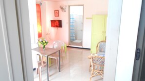A bright room with a dining table, chairs, and a wicker chair. - Aquatic Villa Grand Baie Mauritius (Grand-Baie)