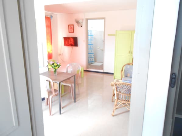 Um quarto claro com uma mesa de jantar, cadeiras e uma cadeira de vime.