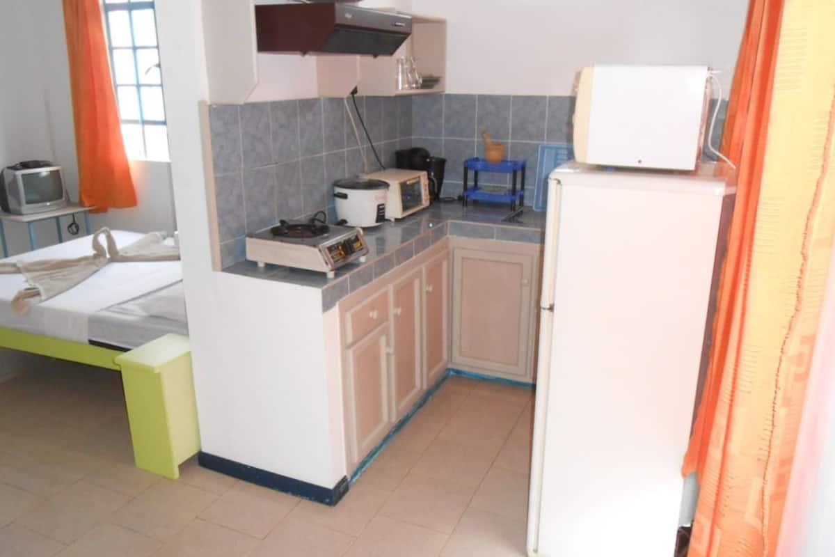 Una cocina compacta con microondas, tostadora y refrigerador pequeño.