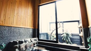 A room with wooden walls, a large window, and a stone bench.
