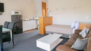 A compact living space with a kitchenette, a dining area, and a bedroom. - Tuki Tuki Motel (Waipukurau)
