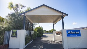 A motel reception with a covered entrance, a sign indicating 50+ channels, and a clear sky. - Tuki Tuki Motel (Waipukurau)