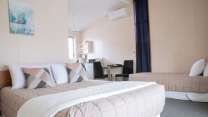 A hotel room with a bed, a desk, a chair, and a window with curtains. - Tuki Tuki Motel (Waipukurau)
