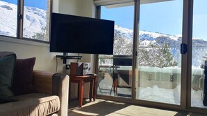 Een kamer met een groot raam, met uitzicht op met sneeuw bedekte bergen.