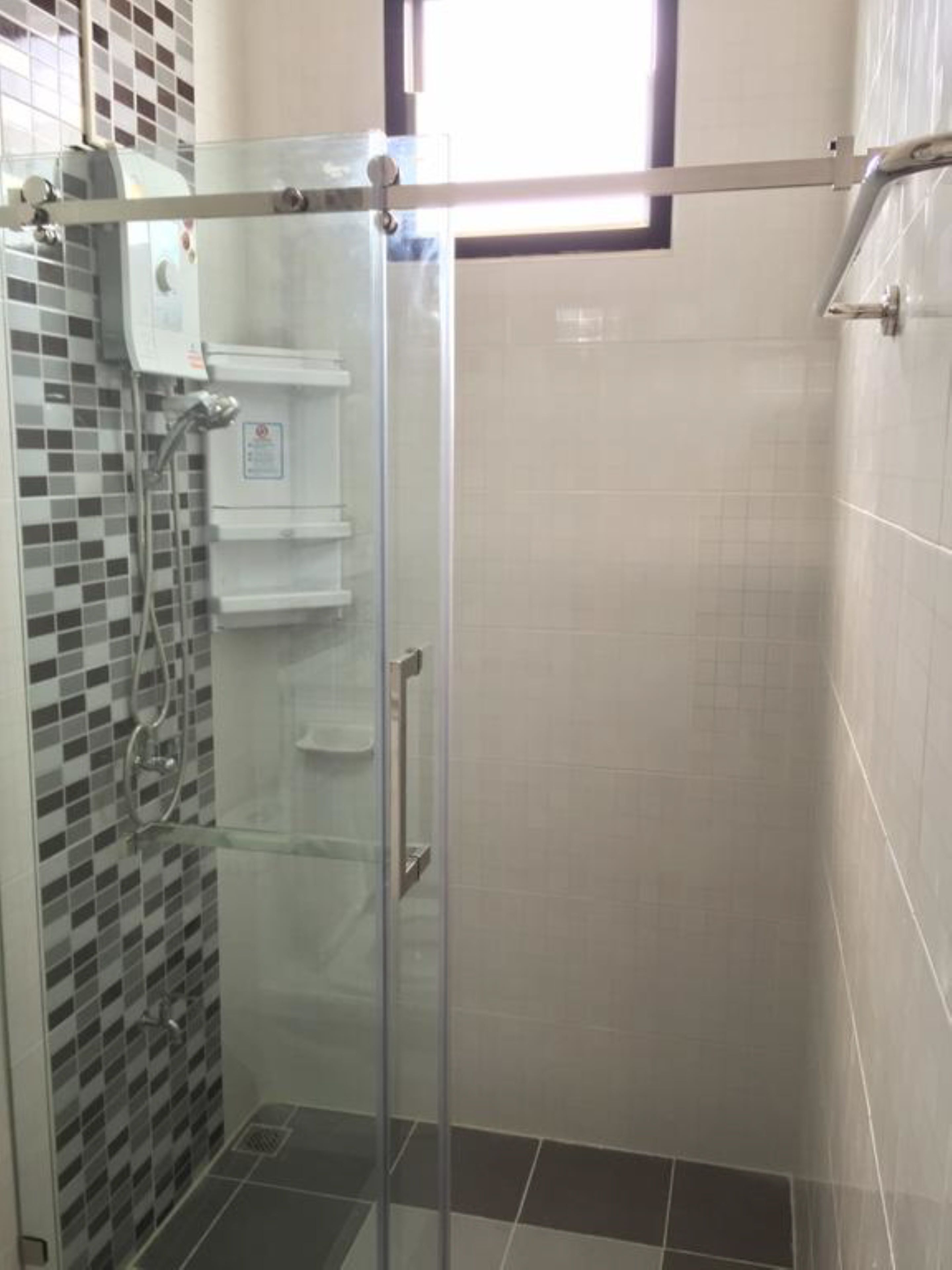 A glass-enclosed shower stall with a tiled floor and a control panel on the wall.