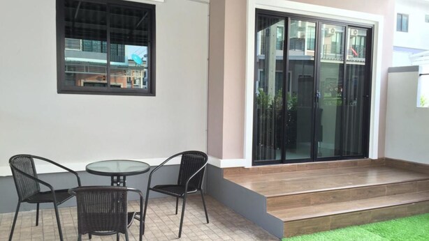 Un espace patio avec une table et des chaises, une petite fenêtre et une porte-fenêtre coulissante donnant sur une entrée abritée.