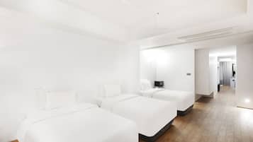 Una habitación de hotel moderna con dos camas individuales, un televisor de pantalla plana y piso de madera.