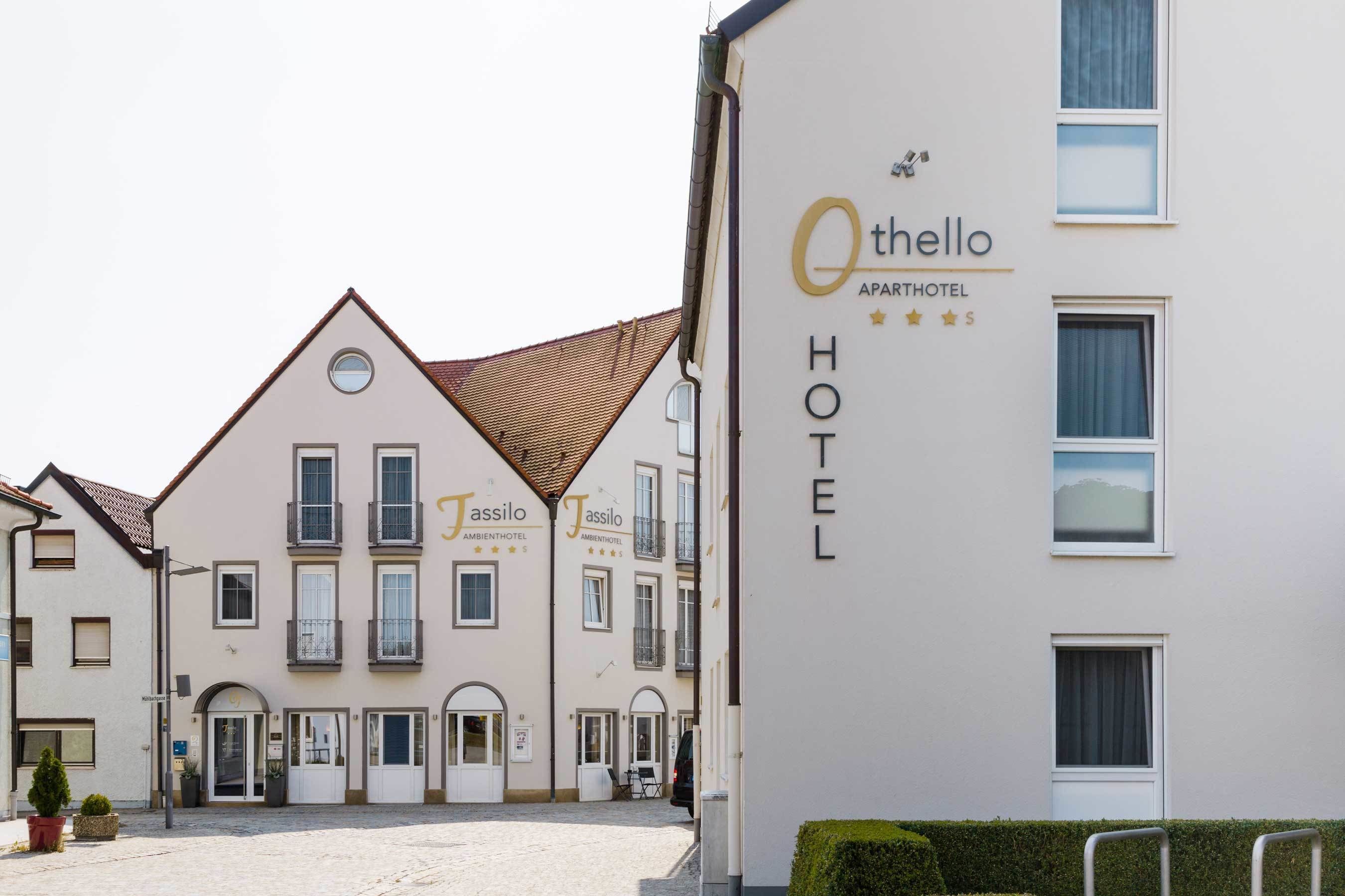 Ein Apartmenthotel Othello mit traditioneller europäischer Architektur, das eine symmetrische Fassade, zahlreiche Fenster und einen zentralen Eingang zeigt.