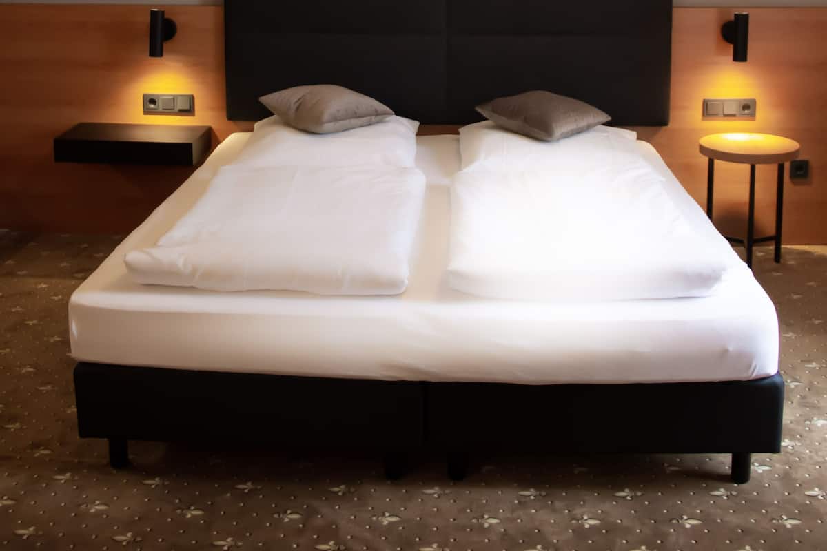 A modern hotel room with a large bed, two bedside tables, and a unique ceiling light fixture.