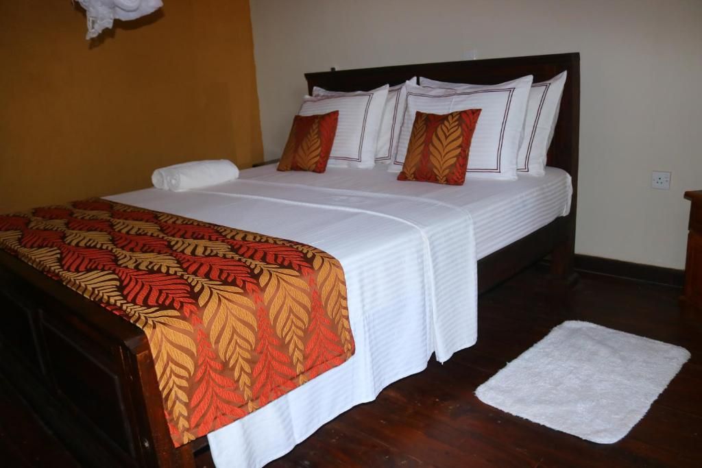 A neatly made bed with a patterned bedspread, a white pillow, and a matching pillow on the headboard.