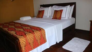 A neatly made bed with a patterned bedspread, a white pillow, and a matching pillow on the headboard.