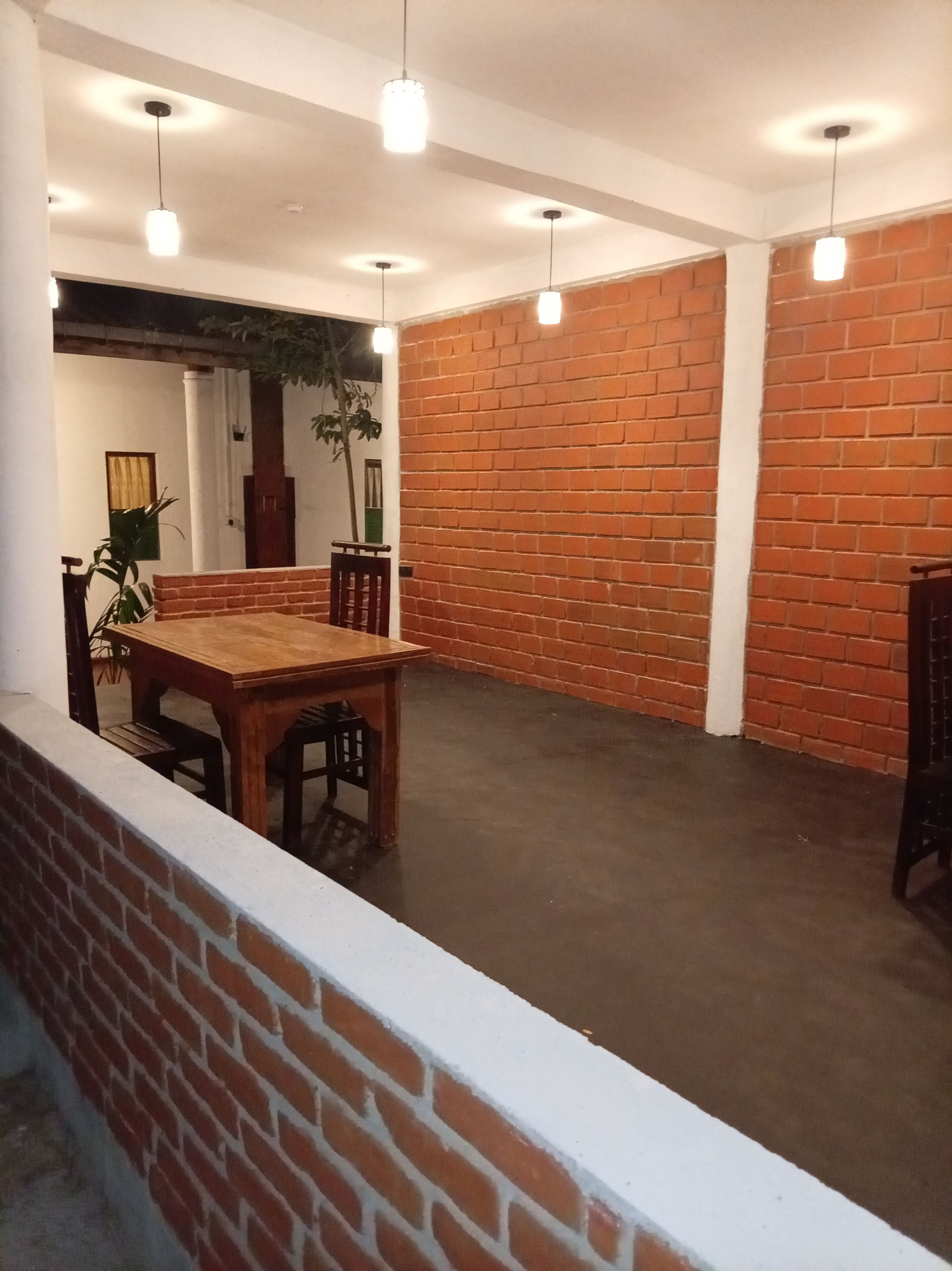 Une pièce spacieuse avec un mur en briques, une table à manger en bois et des lampes suspendues.