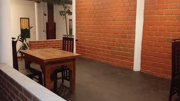 A spacious room with a brick wall, a wooden dining table, and hanging pendant lights.