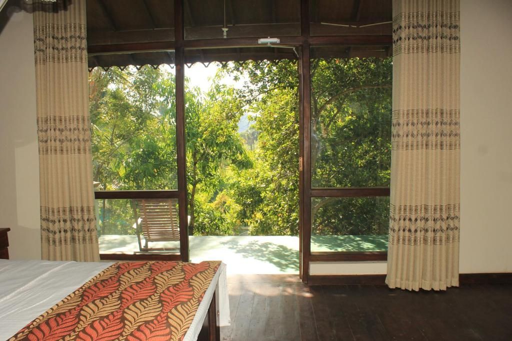 A room with a bed, a window, and a view of trees.