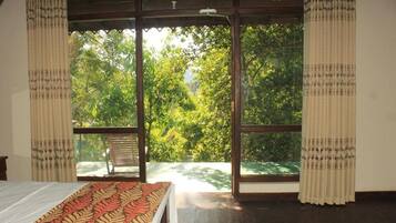 A room with a bed, a window, and a view of trees.