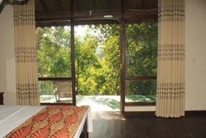 Una habitación con cama, ventana y vista a árboles.