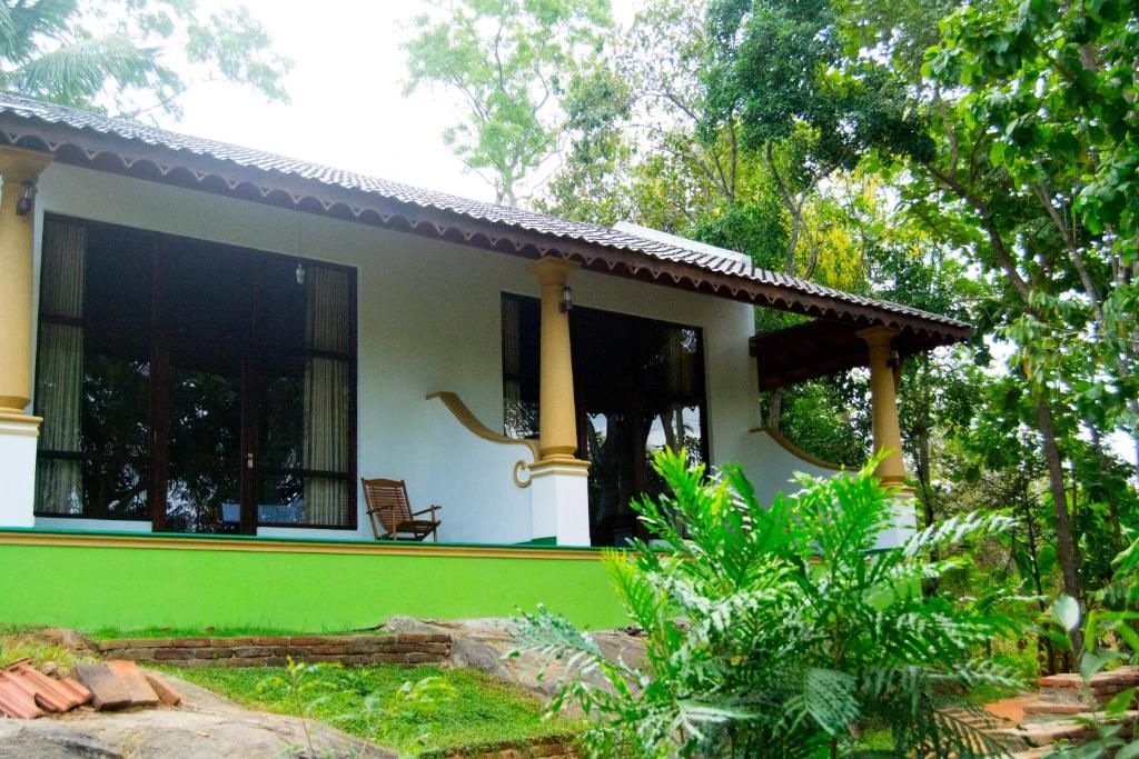A building with a covered porch, large windows, and a green exterior wall.