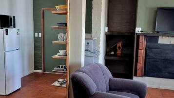 A compact living space with a kitchenette, a grey armchair, and a television.