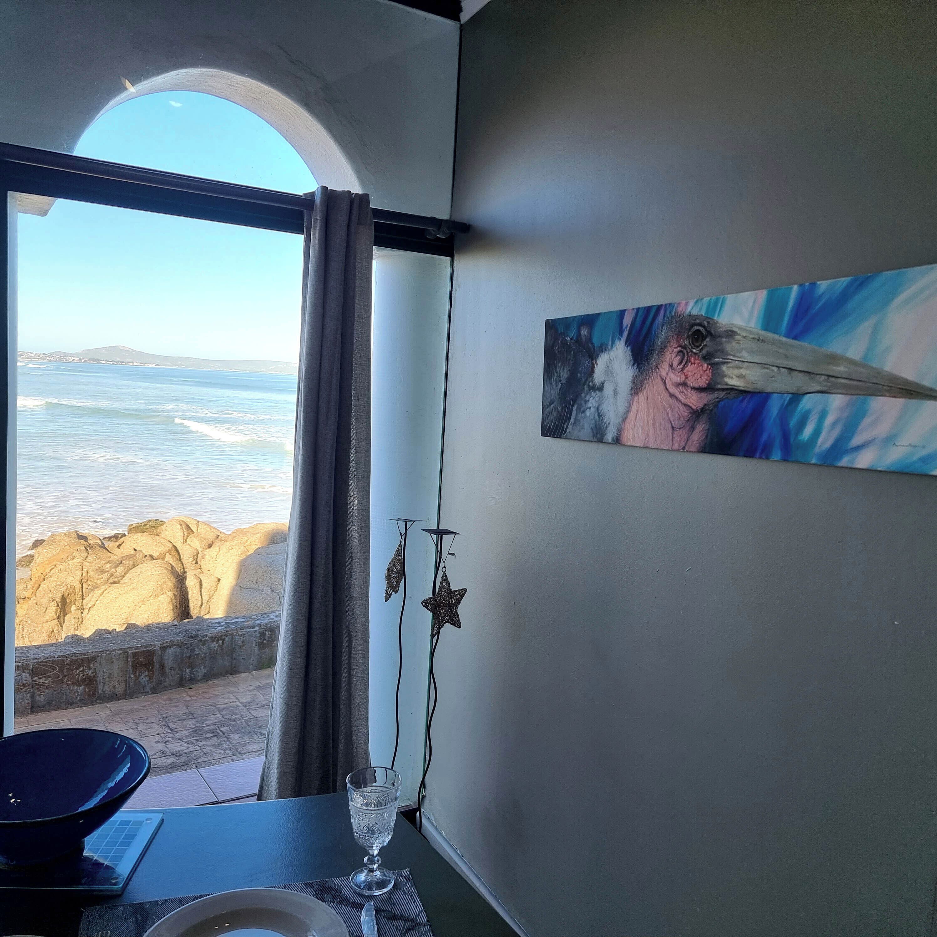 Et værelse med havudsigt, et maleri på væggen og et bord med et glas og en skål.