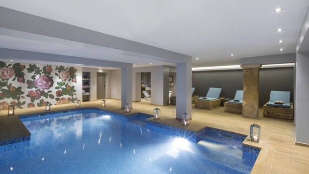 A modern indoor swimming pool with a floral mural, lounge chairs, and recessed lighting. - Luxury Design Hotel Particulier le 28 (Aix-en-Provence)