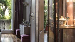 A room with a glass display cabinet containing decorative items, a wooden bench, and a view of greenery outside. - Luxury Design Hotel Particulier le 28 (Aix-en-Provence)